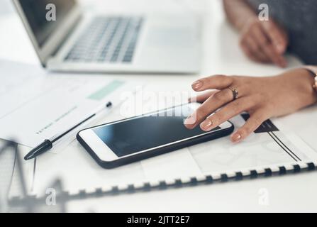 Business woman, marketing analyst and entrepreneur browsing, texting and planning on a phone with a blank screen while working in an office. Closeup Stock Photo