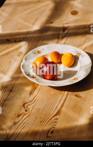 Apricots and nectarines in a bowl on a wooden table in August evening light Stock Photo