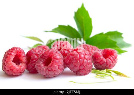 Isolated berries. Pile of raspberry fruits with leaves isolated on a white background with clipping path Stock Photo