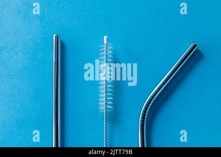 reusable stainless steel straws and cleaning brush on blue background, eco friendly lifestyle, copy space, top view, flat layout. Stock Photo