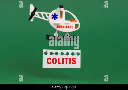 Medical concept. On a green surface, an ambulance helicopter with a sign - COLITIS Stock Photo