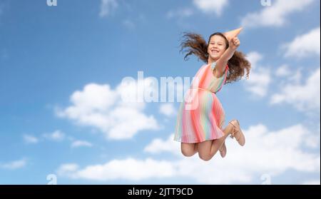 smiling little girl in birthday party hat jumping Stock Photo