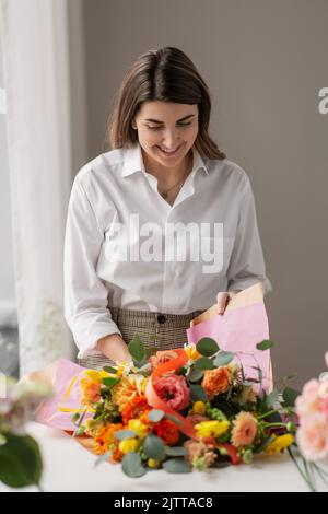 woman wrapping flowers to craft paper at home Stock Photo