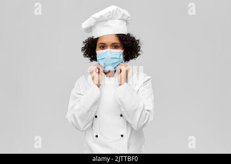 female chef in medical mask and toque Stock Photo