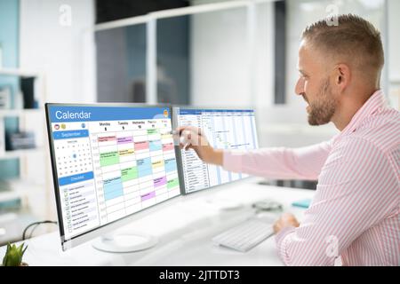 Employee Working On Calendar Schedule And Staff Time Sheet Stock Photo