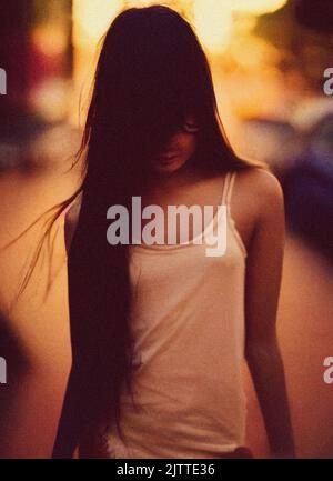 A beautiful young shy woman with long hair covering her face Stock Photo