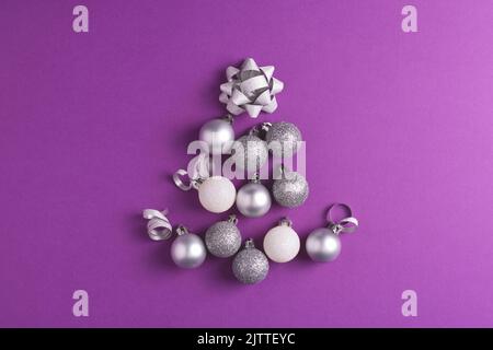 Christmas tree made of metallic baubles on purple background. Top view. Christmas and New Year concept. Stock Photo