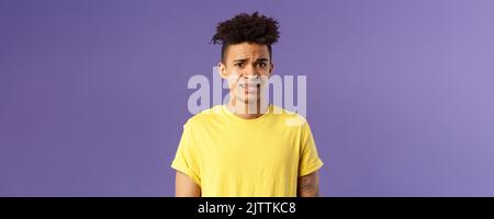 Close-up portrait of awkward and embarrassed young hispanic guy looking ...