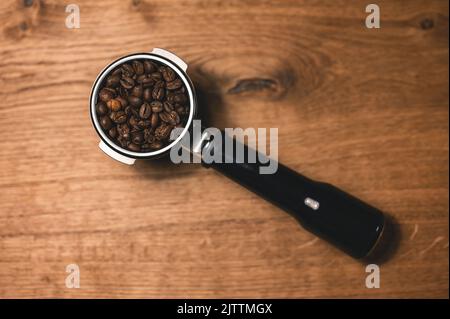 Roasted coffee beans in portafilter on wooden table - flat lay Stock Photo