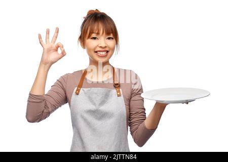 happy woman in apron with empty plate Stock Photo