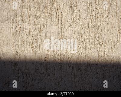 Beige textured wall with shadow and plaster applied with putty knife in irregular dashes and strokes Stock Photo