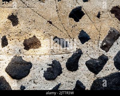 Beige plastered wall with black stones Stock Photo