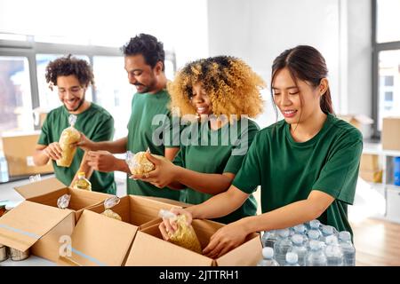 happy volunteers packing food in donation boxes Stock Photo