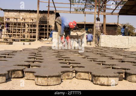 A man is seen laying pavers to dry in Lilongwe. The pavers are made by hand from cement and sand. Malawi. Stock Photo
