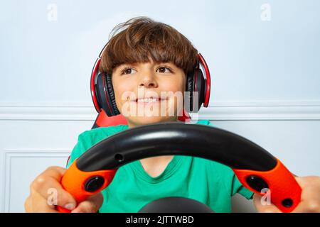 Smiling happy gamer boy with steering wheel play race game Stock Photo
