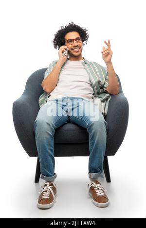 smiling man sitting in chair calling on smartphone Stock Photo