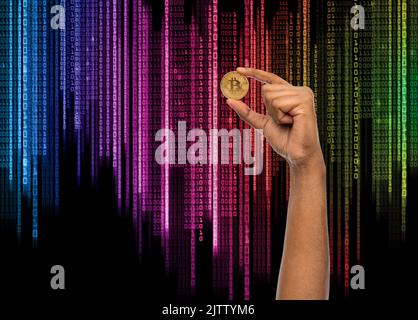 close up of hand with bitcoin over binary code Stock Photo
