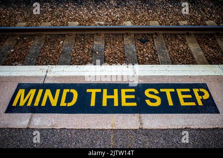 Mind The Step Sign on a British Railway Station Platform. Railway Station Platform Safety Sign. Stock Photo