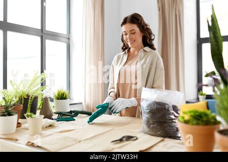 happy woman with gloves planting flowers at home Stock Photo
