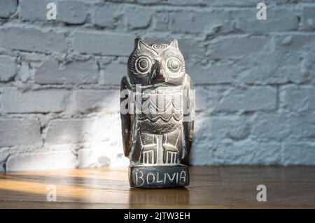 Close up of traditional bolivian owl statuette isolated on white brick wall Stock Photo