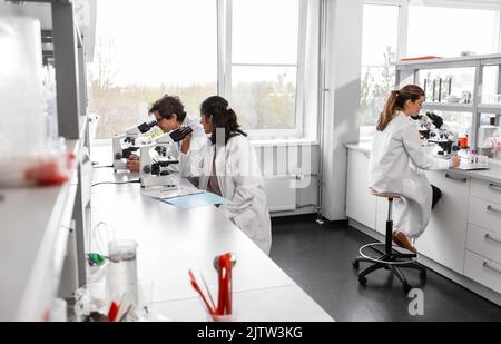 scientists with microscopes working in laboratory Stock Photo