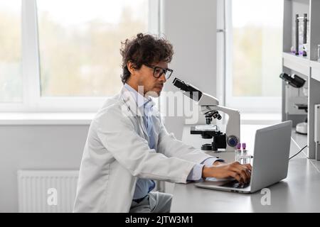 scientist with microscope working in laboratory Stock Photo