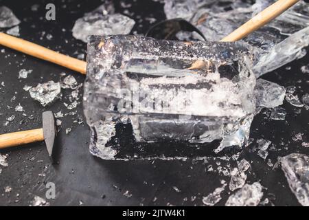 Process of breaking the ice with hammer and ice pick, group of people smashing shattered ice cube, team work success concept, concept of starting even Stock Photo