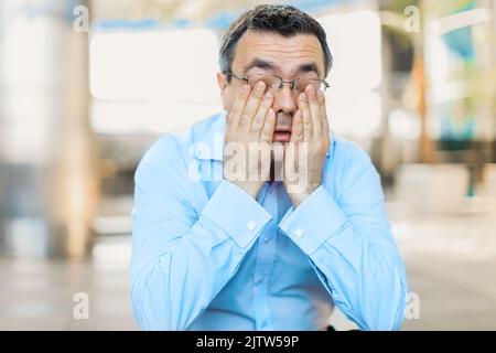Burned out businessman with head in his hands. Businessman in office totally stressed out. Stock Photo