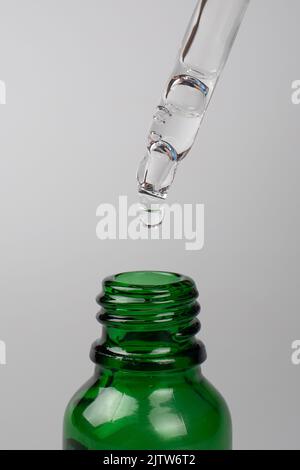 falling drop from a pipette into a green jar. natural and beauty skin care. Stock Photo