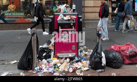 Overflowing litter bin with many full plastic bags on the pavement in Buchanan Street, central Glasgow, during a strike by Council garbage collectors Stock Photo