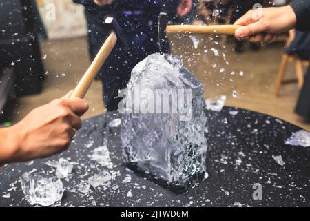 Process of breaking the ice with hammer and ice pick, group of people smashing shattered ice cube, team work success concept, concept of starting even Stock Photo