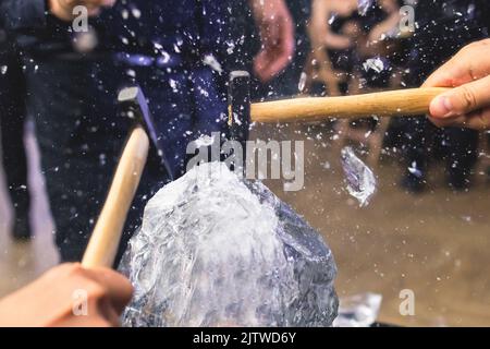 Process of breaking the ice with hammer and ice pick, group of people smashing shattered ice cube, team work success concept, concept of starting even Stock Photo