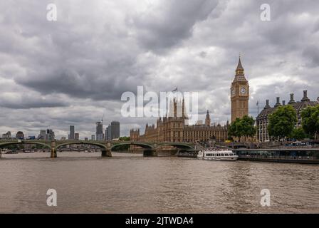 London, England, UK - July 6, 2022: From Thames River. Wide view Boat traffic at Westminster Pier and bridge, with Big Ben and Palace in back under gr Stock Photo
