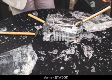 Process of breaking the ice with hammer and ice pick, group of people smashing shattered ice cube, team work success concept, concept of starting even Stock Photo