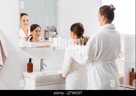 mother and daughter braiding hair at bathroom Stock Photo