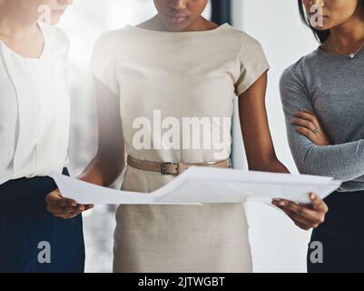 Behind big decisions comes big data. a group of businesswomen analyzing paperwork together. Stock Photo