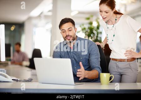 Theyre getting closer to a solution. colleagues working together on a laptop in an office. Stock Photo