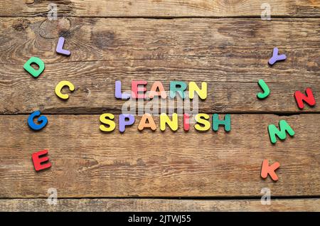 Text LEARN SPANISH and letters on wooden background Stock Photo