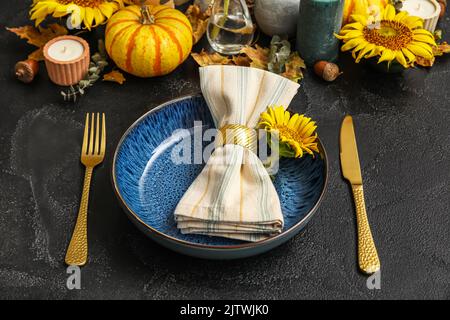 Dinnerware with sunflower in plate and autumn decor on dark table Stock Photo
