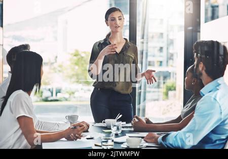 Managing her team as a strong leader. a businesswoman giving a presentation to her colleagues in a boardroom. Stock Photo