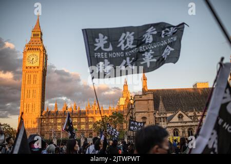 London, UK. 31st Aug, 2022. A protester waves a banner in front of the Palace of Westminster during the demonstration. Protesters gathered in London on the third anniversary of the Hong Kong police entering a metro station and beating protesters and commuters, an event that pro-democracy activists say exemplify the impunity and abuse of the Hong Kong police. Credit: SOPA Images Limited/Alamy Live News Stock Photo