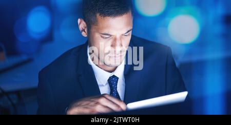Businessman with digital tablet overtime for data research in a corporate office at night. Male entrepreneur and executive worker using technology to Stock Photo
