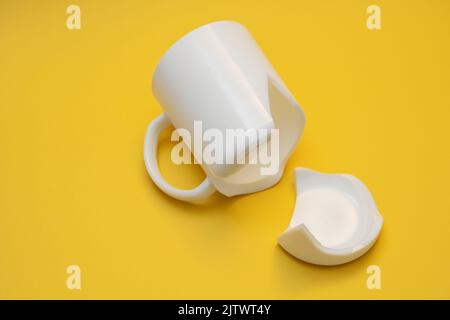 Splinters of the broken tea mug on a yellow background. Stock Photo