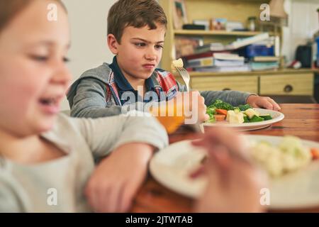 What is this stuff, anyway. two grumpy children refusing to eat their vegetables. Stock Photo