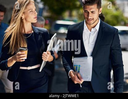 They do their best work together. two corporate colleagues having a discussion while walking down the street on their way to work. Stock Photo