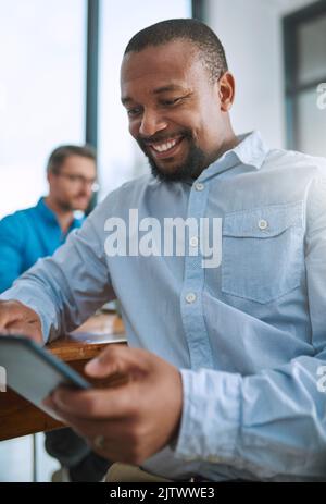 Hes happy with his new resource. a businessman using his tablet with a colleague in the background. Stock Photo