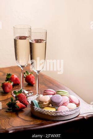champagne and macarons with strawberries on a wooden table Stock Photo