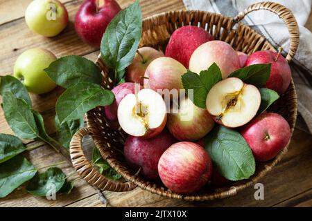 Organic fruits. Fall harvest background. Farmer's market. Basket of ripe apples on a rustic wooden table. Stock Photo
