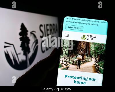 Person holding cellphone with webpage of US environmental organization Sierra Club on screen in front of logo. Focus on center of phone display. Stock Photo