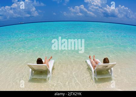 Holidaymaker relaxing on sunbeds in the lagoon of the maldivian island Biyadhoo, South-Male Atoll, Maldives, Indian ocean, Asia Stock Photo